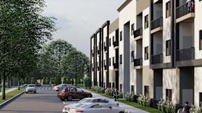 A street view of a residential area with cars parked on the side of the road and apartment buildings on the right.