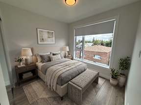 A bedroom with a large bed and a window overlooking a building.