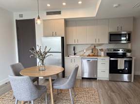 A modern kitchen with a round table and grey chairs.