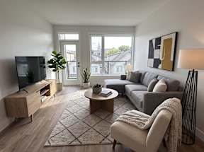 A living room with a grey couch, a coffee table, a television, and a large window.