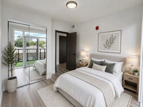 A bedroom with a large bed, a potted plant, and a framed picture on the wall.