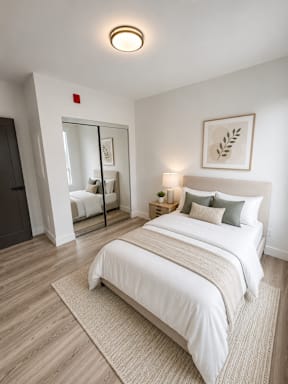 A bedroom with a large bed and a mirror.