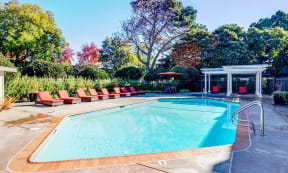 a swimming pool with red lounge chairs around it