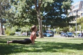 a woman doing yoga in the grass in a park