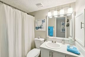 A white bathroom with a toilet, sink, and shower curtain.