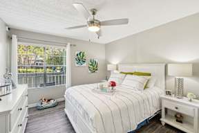 A bedroom with a bed, nightstand, and a fan.