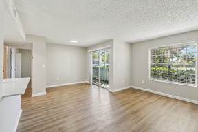 A spacious room with wooden floors and white walls.