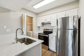 A kitchen with a stainless steel refrigerator, sink, and oven.
