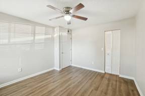 A room with a ceiling fan and wooden flooring.