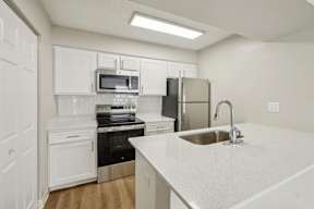 A kitchen with white cabinets and a stainless steel refrigerator.