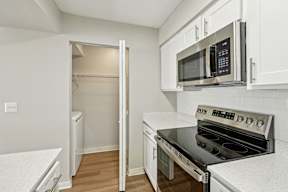 A kitchen with a black stove top oven and white cabinets.