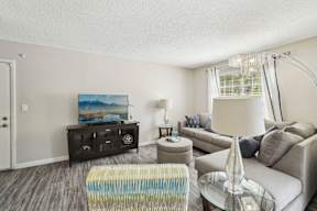 A living room with a grey couch, a coffee table, and a painting on the wall.