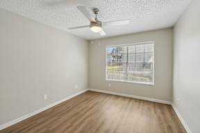 Empty room with a ceiling fan and a window with blinds.
