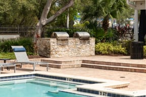 a swimming pool with two bbq pits next to a resort style pool