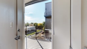 a door that is open to a balcony with a view of a parking lot
