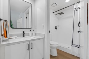 a bathroom with white cabinets and a white toilet next to a white bathtub