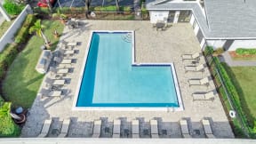 an aerial view of a swimming pool in a backyard with lounge chairs