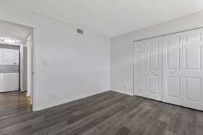 a bedroom with white walls and wood flooring