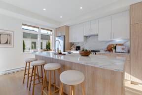 A kitchen with a marble countertop and wooden stools in Hillcrest Ave located in Abbotsford, BC