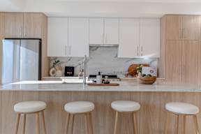 A kitchen with white cabinets and a marble backsplash in Hillcrest Ave located in Abbotsford, BC