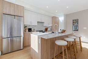 A modern kitchen with a stainless steel refrigerator and wooden cabinets in Hillcrest Ave located in Abbotsford, BC