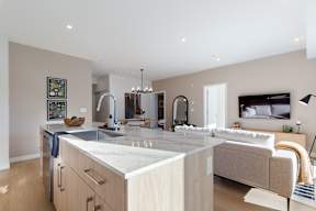 A modern kitchen with a large island and a living area with a couch in Hillcrest Ave located in Abbotsford, BC