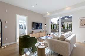 A living room with a green chair and a beige couch in Hillcrest Ave located in Abbotsford, BC