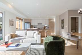 A modern living room with a white sofa, green armchair, and a coffee table in Hillcrest Ave located in Abbotsford, BC