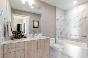 A bathroom with a marble wall and a white bathtub in Hillcrest Ave located in Abbotsford, BC