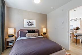 A bedroom with a large bed and a painting above it in Hillcrest Ave located in Abbotsford, BC