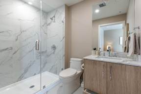 A bathroom with a marble tile shower and a white toilet in Hillcrest Ave located in Abbotsford, BC