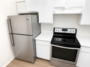A stainless steel refrigerator and oven in a kitchen located at Canfield Lakes Apartments in Houston TX