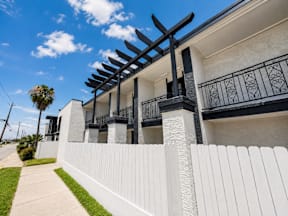 A white apartment building with a black railing and a black pergola located at the pointe apartments in Pasadena, Tx