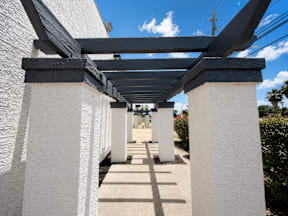 A long corridor with white walls and a roof supported by white pillars located at the pointe apartments in Pasadena, Tx