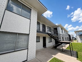 Apartment building with a black metal staircase located at the pointe apartments in Pasadena, Tx