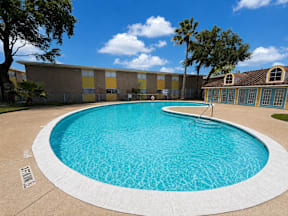 Spacious swimming pool with trees located at the pointe apartments in Pasadena, Tx
