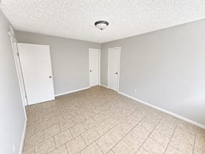 A room with a white ceiling, two doors, and a tiled floor with walk in closets located at the pointe apartments in Pasadena, Tx