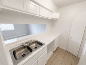 Spacious kitchen with a double sink, window and closet located at the pointe apartments in Pasadena, Tx