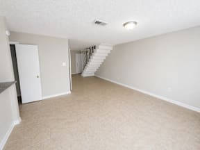 A spacious living room with a staircase leading upstairs located at the pointe apartments in Pasadena, Tx