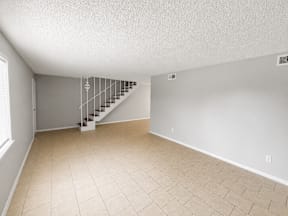 Spacious living room with tiled flooring and staircase located at the pointe apartments in Pasadena, Tx