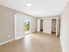 Living room with glass sliding door to balcony located at the pointe apartments in Pasadena, Tx