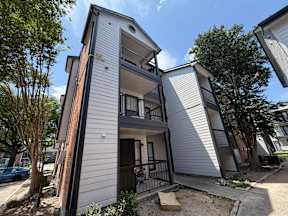 A modern two-story apartment building with a balcony on the second floor located at Canfield Lakes Apartments in Houston TX