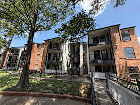 A row of townhouses with a black fence in front located at Canfield Lakes Apartments in Houston TX