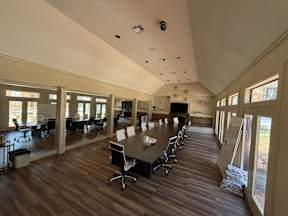 A conference room with a long table and chairs is shown located at Canfield Lakes Apartments in Houston TX