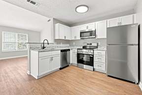 A kitchen with a refrigerator, oven, and microwave.