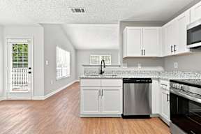 A kitchen with white cabinets and a wooden floor.