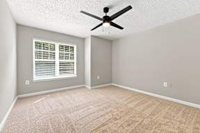 A room with a ceiling fan and a window with blinds.