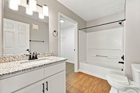 A white bathroom with a granite counter top and a walk-in shower.