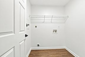 A white door is on the left of a room with a shelf above it.