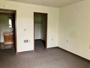 A bedroom with a carpeted floor and two open doors.